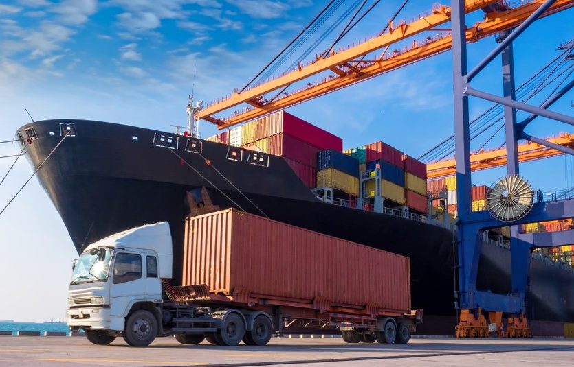 This is an image of a truck next to a cargo ship