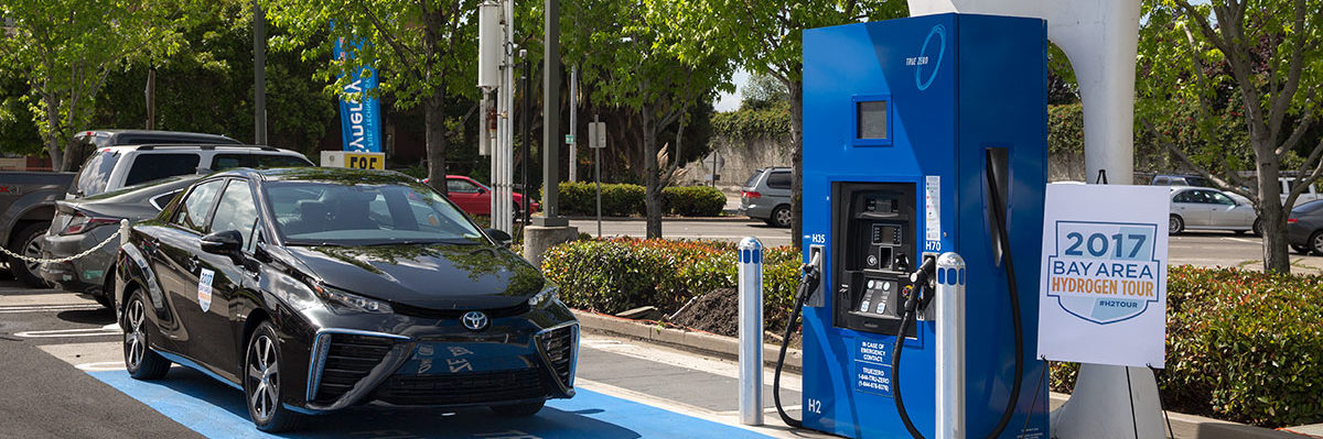 Image of a fuel cell vehicle pulling up to a hydrogen fueling station